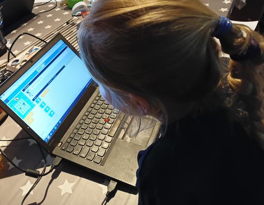 Ein blondes Kind mit Zopf sitzt vor ihrem ThinkPad x270. Ihr Gesicht ist nicht zu erkennen. Auf dem Gerät läuft Kubuntu, im Browser ist eine Übung von code.org offen, sie liest sich Gerade die Aufgabe durch.