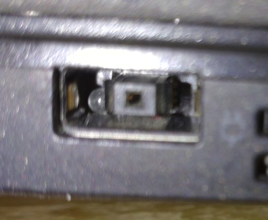 Eine kleine durchsichtige Kugel steckt in der linken Seite einer rechteckigen Thinkpad Ladebuchse.