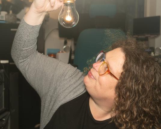 Gemma holding a glowing lightbulb, looking up at the lightbulb