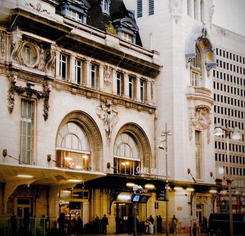 La photographie représente la façade inférieure la gare de Lyon à Paris, y compris ses éléments détaillée et de ses éléments décoratifs. Un autre bâtiment est visible sur la droite de l'image, avec une architecture neutre, un bloc de béton avec plein de fenêtre. La différence d'architecture crée un contraste dans l'image.