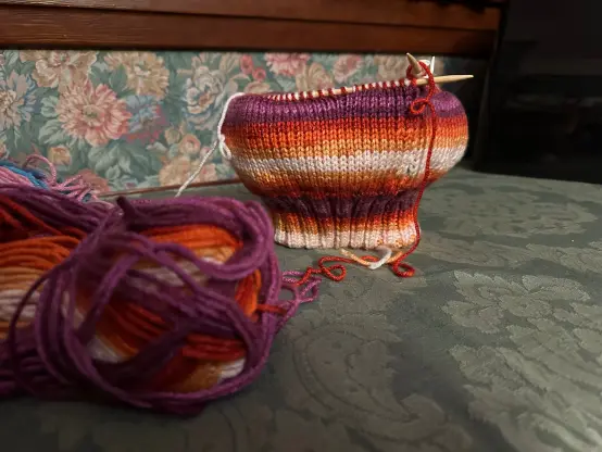 the outside of my reversible trans/lesbian pride doubleknit tam with a messy skein of yarn in the foreground