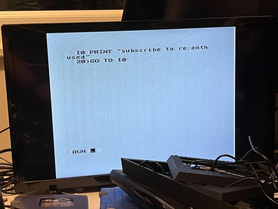A Sinclair Spectrum BASIC screen with two lines of text the first printing text that says Subscribe to re:enthused and the second a goto to the first line