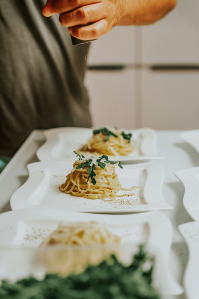 Three beautifully plated piles of cacio e pepe pasta, mid-preparation.