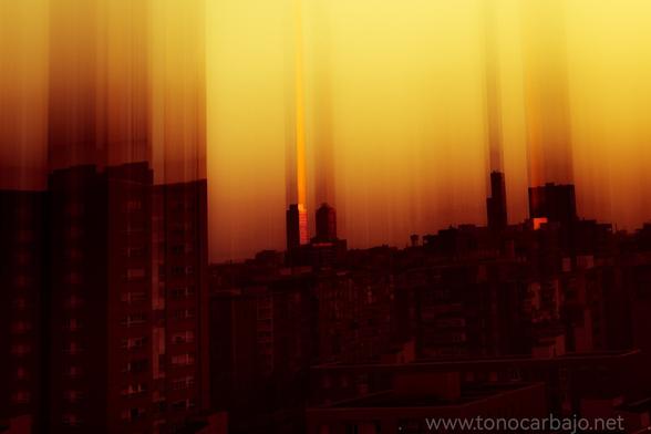 Vista del Skyline de Barcelona durante la puesta de sol. Se ha usado un filtro analógico cokin que hace que los edificios se vean como desplazados hacia arriba. El color anaranjado tiñe la imagen.