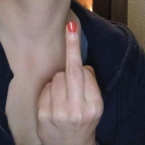 Mittelfinger mit pinkem Nagellack 
Dahinter ein Mensch im dunklen Hoodie