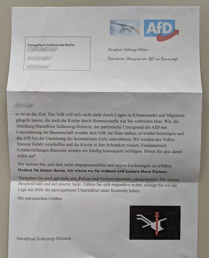 Der Text an den Pfaffer lautet:

Es ist an der Zeit: Das Volk will sich nicht mehr durch Lügen zu Klimawandel und Migration gängeln lassen, die auch die Kirche durch Homosexuelle wie Sie verbreiten lässt. Wir, die Abteilung Sturmfront Schleswig-Holstein, der patriotische Untergrund der AfD mit Unterstützung der Bauernschaft, werden dem Volk zur Seite stehen, es wieder bereinigen und die AfD bei der Umsetzung der heimattreuen Ziele unterstützen. Wir werden des Volkes Stimme Gehör verschaffen und die Kirche in ihre Schranken weisen. Fundamentale Fehldarstellungen Ihrerseits werden wir künftig konsequent verfolgen. Hören Sie also damit sofort auf!

Wir warnen Sie, sich dem nicht entgegenzustellen und unsere Forderungen zu erfüllen. Denken Sie immer daran, wir wissen wo Sie wohnen und kennen Ihren Partner.

Versuchen Sie auch gar nicht erst, Polizei und Verfassungsschutz einzuschalten. Die wissen Bescheid und sind auf unserer Seite. Fühlen Sie sich nirgendwo sicher, solange bis wir die Lage mit Hilfe der parteigetreuen Unterstützer unter Kontrolle haben.

Mit patriotischen Grüßen
Sturmfront Schleswig-Holstein