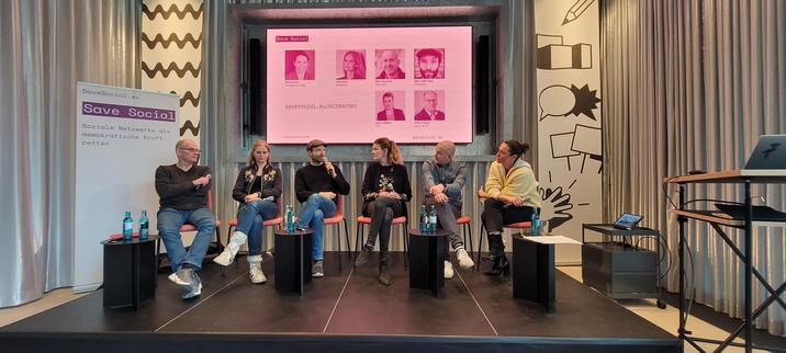 Six persons on a stage, background presenation names them as (from left) Peter Freitag (dju in v er.di), singer Dota Kehr, writer Marc-Uwe Kling, Hanna Möllers (DJV), Björn Staschen (initator Save Social) and Maria Exner (Publix).
