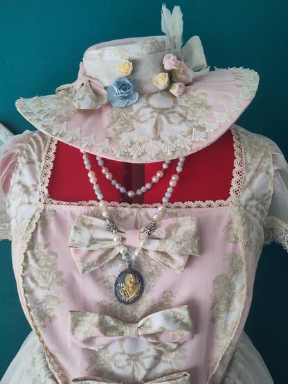 Hat handmade by MercuRea brand, with pale pink fabric with a beige damask print, in rococo style, with feathers and flowers