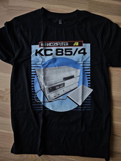 Photo of a T-shirt with a KC-85/4 computer from the East-German VEB Mühlhausen. The design is blue and reminiscent of the casette inlays for said computer. On the top it reads Kleincomputer