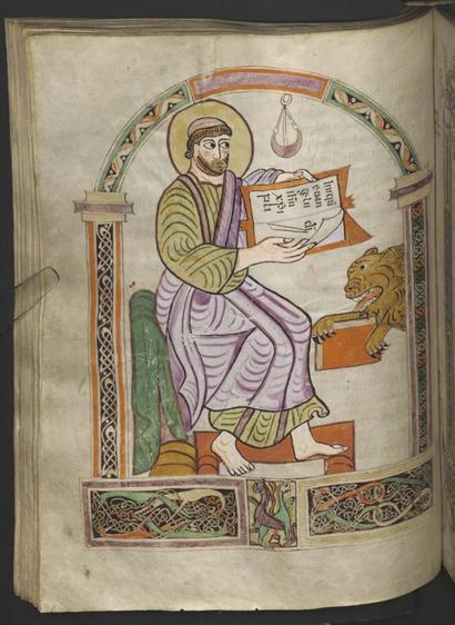 Full-page medieval manuscript illumination in green, purple and orange tones, with a man sitting under an arch holding a book at shoulder height, beneath which the front half of a lion is licking a closed book.
