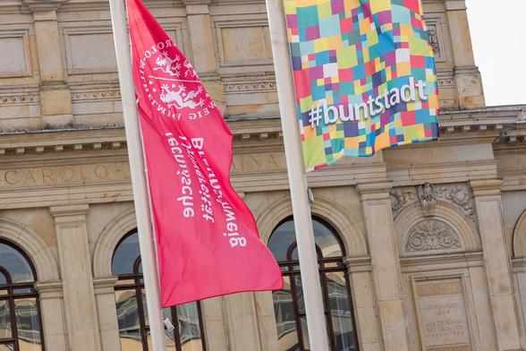 Die Flagge der TU Braunschweig und die Buntstadt-Fahne wehen vor dem Altgebäude der Universität.

Foto: Kristina Rottig/TU Braunschweig