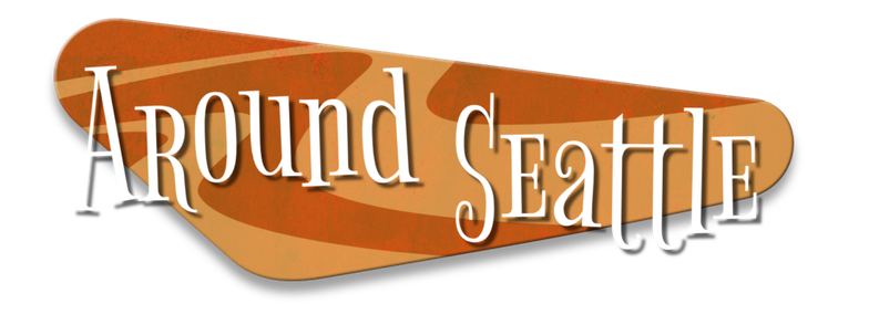 The text Around Seattle against a retrofuturistic design of a rounded triangle shape with an orangey swirl pattern.