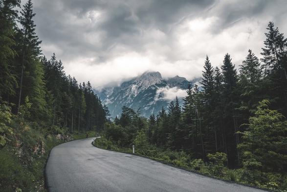 A road that seems to lead to a mountain range with dense forest on both sides.