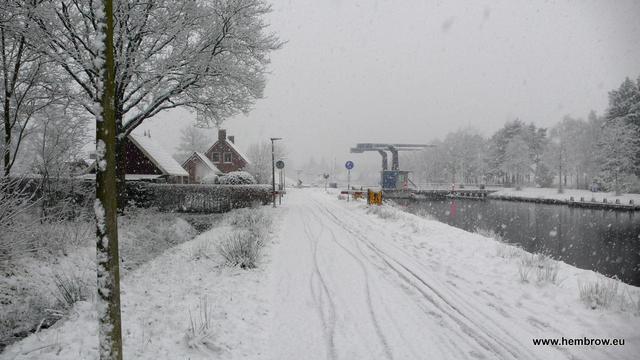 Cycle-path during snowfall. Everything's white, but for a few bicycle tyre tracks in the snow. In the distance there's a bridge and a lonely cyclist (it's quite a busy route, but only one bike visible in this photo)
