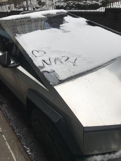 A Cybertruck or Wankpanzer or Swasticar with snow on the ridiculously large windshield. Someone has, with their finger, traced a heart symbol and the word nazi in the snow. There is also a parking ticket because this piece of shit parked in an emergency zone before the storm.