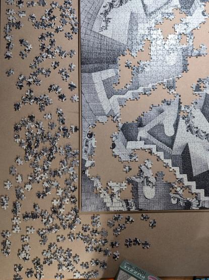 Several shades of grey, a puzzle half-made and half in pieces surrounding the fitted half.