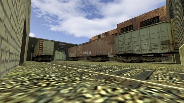 In this picture you can see Trainyard B again. This time from a very low position, which is in front of the part of the parking rails with roof and in front of the opposite of gate four. In addition, you can see the entrance to Trainyard A on the left. Furthermore, you can see four container wagons. Two of them white and two of them red. Between the left and the middle track is the electrical box. This is on the map de_train in the game Coubter-Strike 1.6.