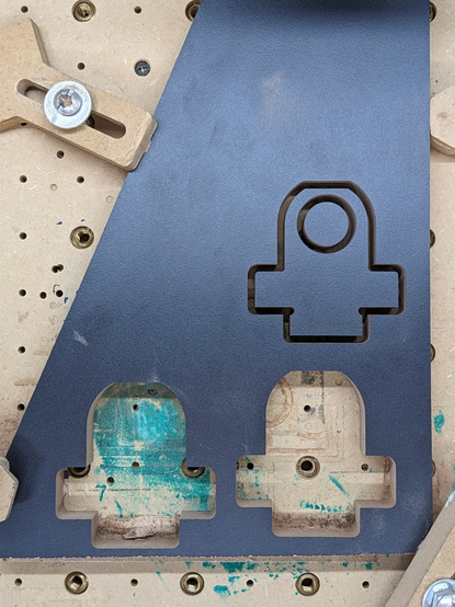 another view of the result of the CNC job. In this case you can see the whole where two pieces were cut and a third piece still attached to the board by some tags