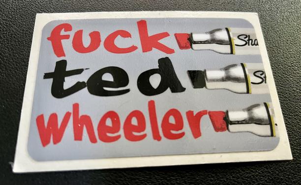 Sticker that reads “fuck Ted Wheeler.” Each word is on its own line with a permanent marker next to it, as if being hand written by them. Two lines in red, the middle in black.