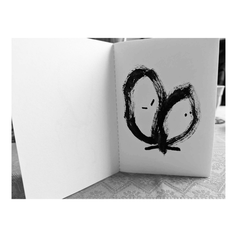 Petit cahier brut avec une série de dessins intuitifs et spontanés dessinés au feutre pinceau noir.