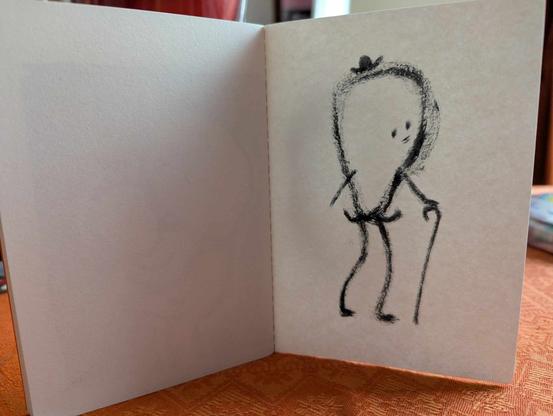 Petit cahier brut avec une série de dessins intuitifs et spontanés dessinés au feutre pinceau noir.