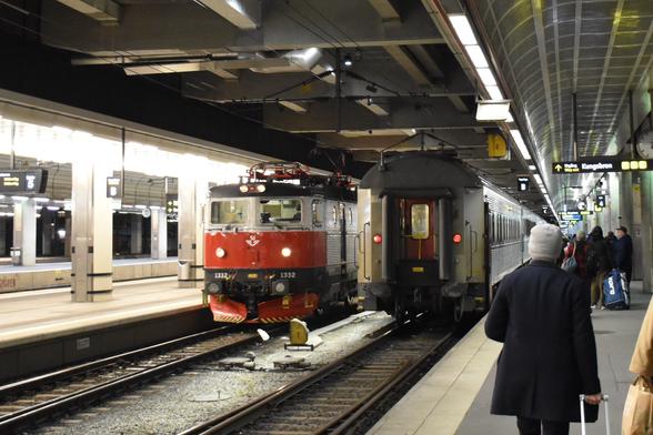 Train on the Stockholm Central station. On one track there are coaches and on the adjacent track the locomotive is going around to the other side.