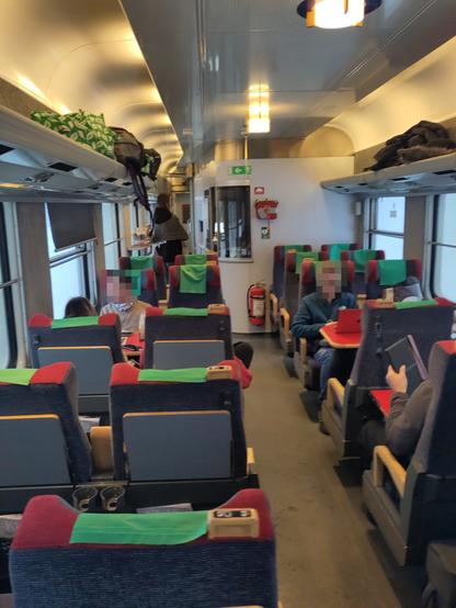 A view inside a coach. There are normal seats, without compartments. There's a small cabin inside with an open window, where snacks are seved.