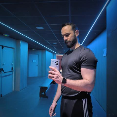 Selfie en el espejo del vestuario del gimnasio. De fondo se ven unas luces de neón azul modo discoteca