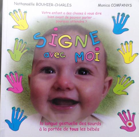 Couverture du livre Signe avec moi (N. Bouhier-Charles et M. Companys) pour apprendre à signer avec un bébé. La couverture est illustrée avec une bouille souriante de bébé, entourée de dessins de mains colorées