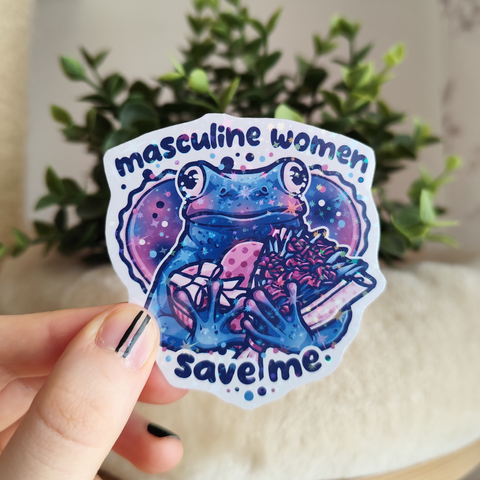 Hand holding up a sticker of a frog carrying a box of chocolates and a bouquet of flowers, titled "masculine women, save me"