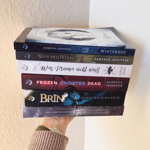 Eine Hand hält einen Stapel Bücher der Autorin Sameena Jehanzeb in die Höhe. Von oben nach unten:

Runa: Eine kurze Geschichte vom Winterhof
Winterhof
Siebensteinthal
Was Preema nicht weiß
Frozen Ghosted Dead
BRÏN
Durch Eiswüsten und Flammenmeere