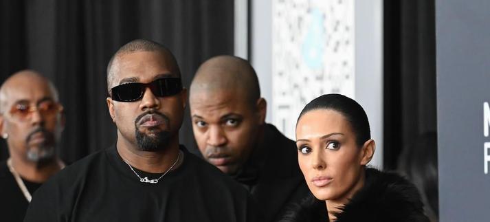 Kanye West, vestido de negro y gafas de solo, y Bianca Censori, con una abrigo grande de pelo, posan en la alfombra roja de la 67ª edición de los premios Grammy en el Crypto.com Arena. / Gilbert Flores