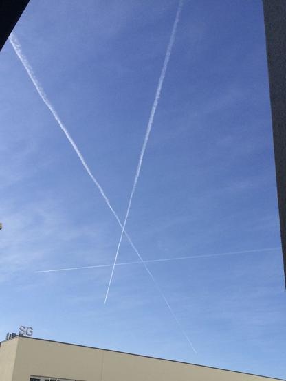 Three contrails (trails of clouds created by airplanes) are crossing in the sky, forming a capital letter A.