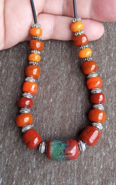 A Handmade Lampwork Glass Bead Necklace in shades of opaque red, set against a light brown background.