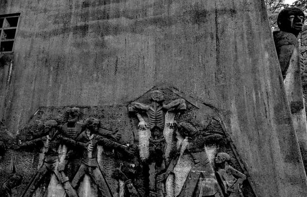 A monochrome photograph depicting a wall filled with statues, honoring the memory of those murdered in Dortmund during Easter 1945.

Eine Schwarzweissfotografie, die eine mit Statuen gefuellte Wand zeigt, die an die Ermordeten von Ostern 1945 in Dortmund erinnert.