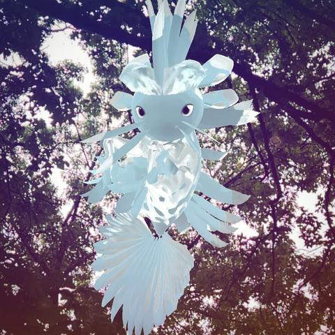 A white and light blue dot with the plumage chaos trait Grassy Blades hovering in the air during a cloudy day. There are trees in the background.