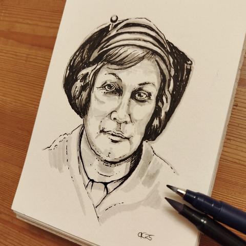 Schulterportrait von Alexandra Povòrina in Grau und Schwarz. Sie trägt eine elegante Mütze und schaut nach vorne. Im kleinen Skizzenbuch mit Stiften.