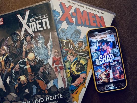 The image shows two X-Men comics and a smartphone with the "Marvel Snap" app open on a brown surface.