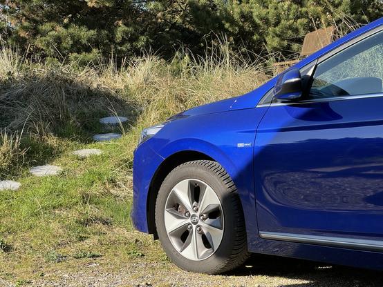 Zu sehen ist die vordere linke Hälfte eines blauen Hyundai Ioniq.
