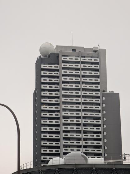 Photo of a gray highrise with metal balconies and spheric objects