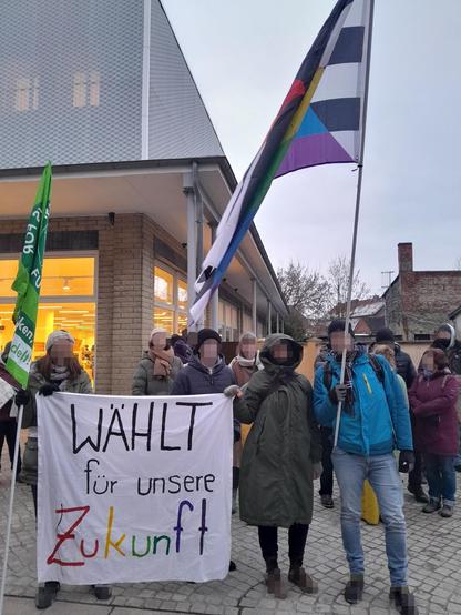 Eine Gruppe von Teilnehmer*innen mit einer Fridays-For-Future-Fahnen und einer Straight-Ally-Fahne. Auf einem Tranzperent steht: "Wählt für unsere Zukunft", wobei Zukunft mit bunten Buchstaben geschrieben wurde.