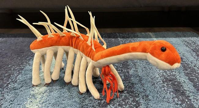 plush toy of a many-legged, spiny backed invertebrate, with a long 'neck'.