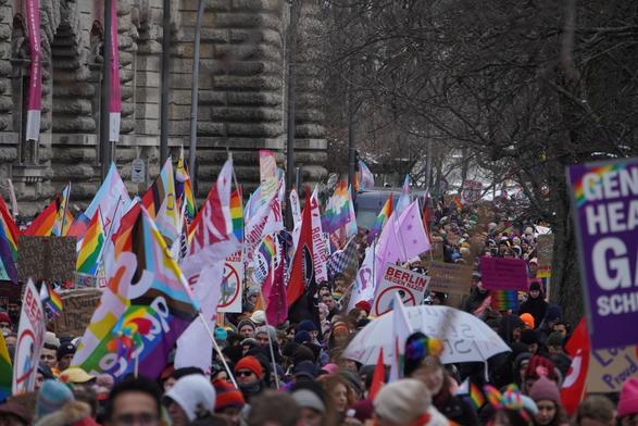 Sehr viele Menschen mit Regenbogenfahnen und Schildern laufen durch die Straße. Es ist kein Ende zu sehen.
