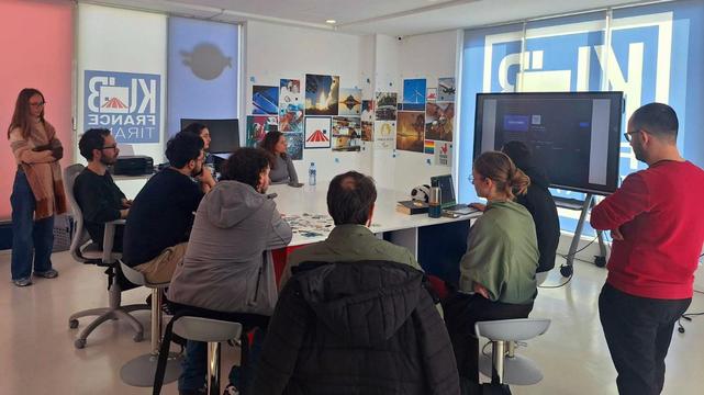 A group of people around a table in front of a large TV.