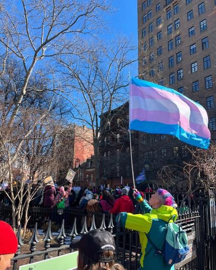 Manifestation avec une personne qui tient un drapeau trans
