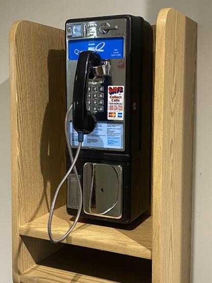 An image of a beautiful Qwest Fortress payphone tucked inside a sleek wooden wall-mounted cubby booth, looking absolutely pristine.