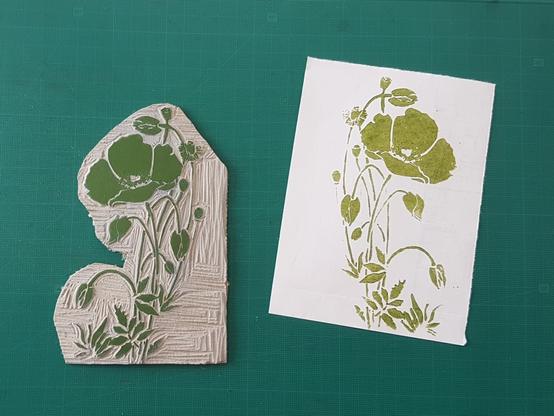 Green linoprint of a poppy on white handmade paper.