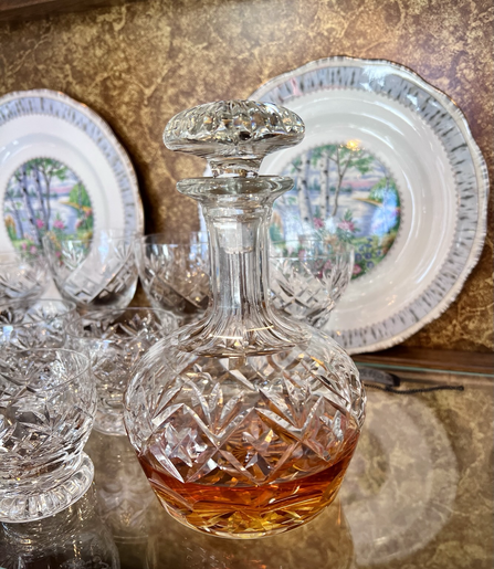 Chrystal whiskey decanter. China plate in the background in the silver birch pattern