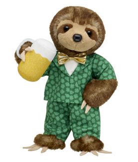 A cuddly sloth toy is seen, wearing a little green suite with a gold bow tie. It is drinking form a cuddly beer glass