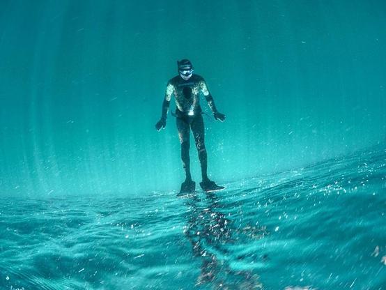 upside down view of someone upside down underwater with their feet touching the surface so it looks like they're standing on the surface